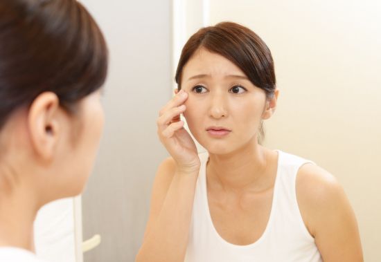 Person noticing a red spot on the eye while looking in the mirror.